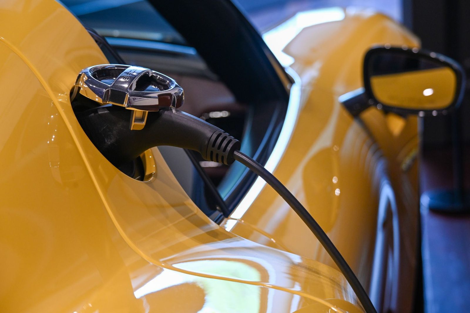 Auto eléctrico amarillo con el cable de carga conectado