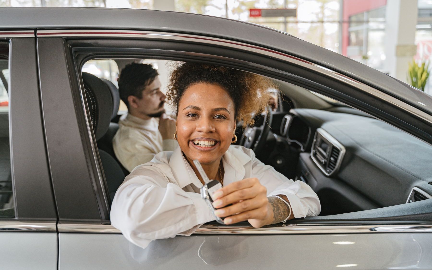 Clienta sonriendo al volante de su auto recién comprado