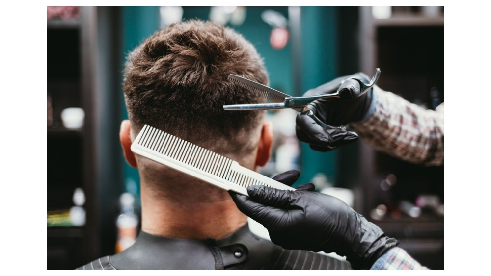 Barbero cortando el cabello con tijera y peine