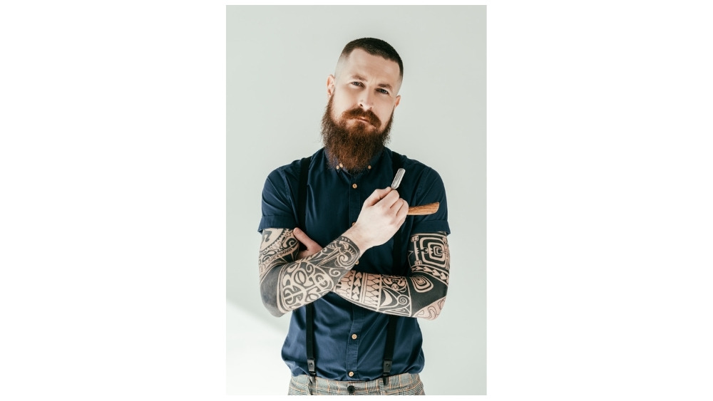 Barbero con tatuajes sosteniendo una navaja
