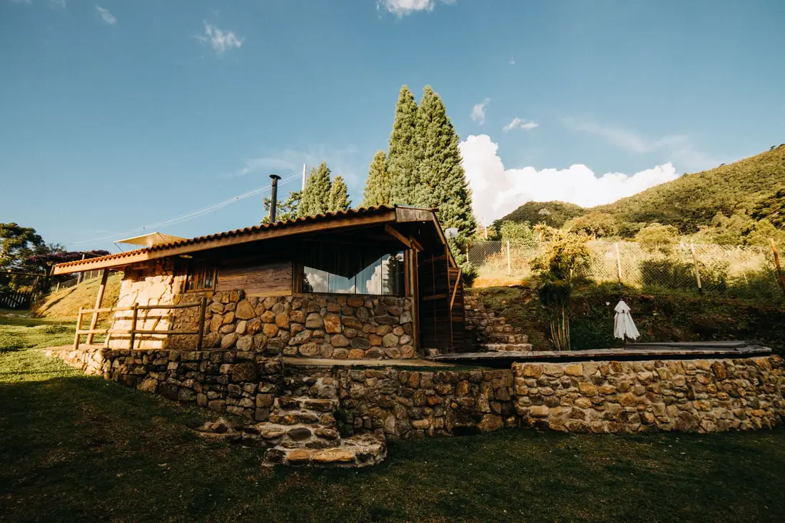 La Piedra: casita de piedra con deck de madera sobre el campo, con lomas detrás